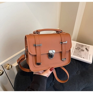 Close-up of caramel vintage crossbody bag with matte finish and silver metal lock