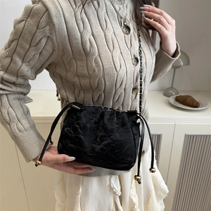 Sac seau plissé noir chic avec bandoulière chaîne dorée dans un cadre de vie chaleureux