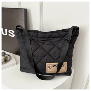 Détail du sac bandoulière matelassé noir avec coutures en losange et étiquette mode