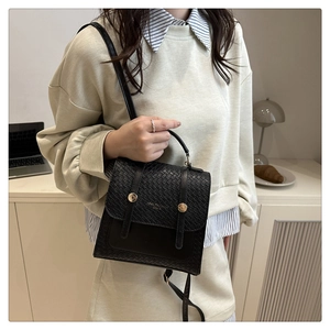 Detail of black woven texture handbag with gold snap buttons and elegant carry handle