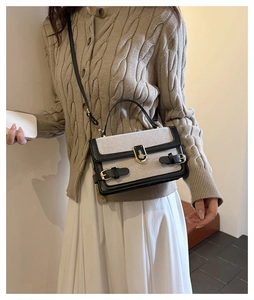 Detail of canvas shoulder bag with black leather trim and round gold metal lock