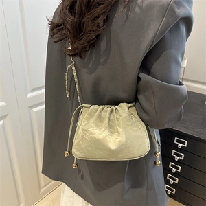 Sac seau vert sauge plissé avec détails dorés et bandoulière en chaîne tressée