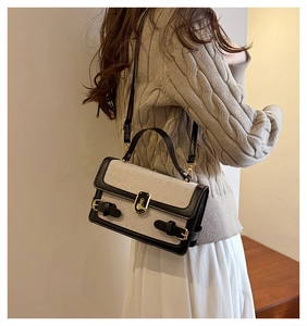 Detail of vintage canvas and black leather crossbody bag with golden turn-lock closure