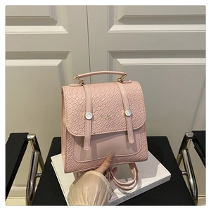 Close-up of pink leather backpack featuring woven texture detail and gold metal buckles