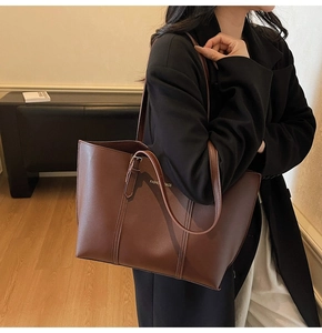 Détail d'un grand sac cabas marron avec fines bandoulières et lettrage doré élégant