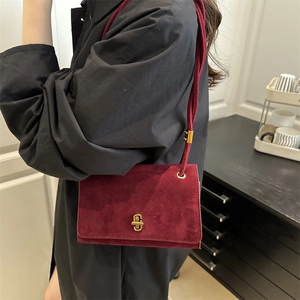 Burgundy suede shoulder bag with gold metal buckle shown from a stylish side angle