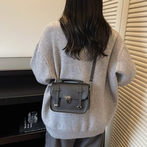 Retro black PU leather crossbody bag with top handle shown on a model in a minimal room
