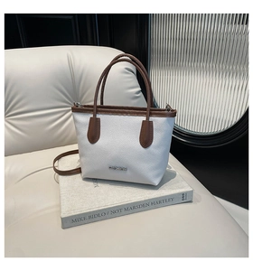Detailed close-up of white and brown textured leather bucket bag on a vintage book