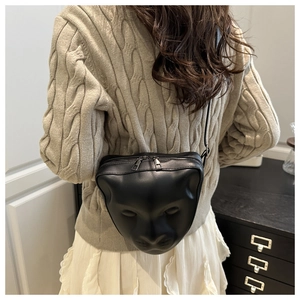 Detail of artistic 3D face relief on a black matte leather crossbody square bag