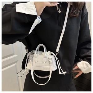 White croc-effect mini bucket bag with drawstring closure and shoulder strap on model