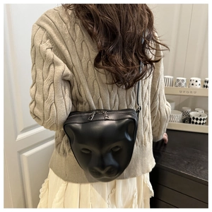 Detail view of stylish black shoulder bag with artistic 3D face relief on matte leather