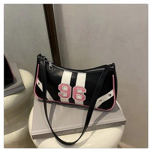 Detail of black faux leather underarm bag with pink trim and number 96 patch embroidery