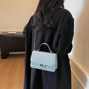 Light blue quilted shoulder bag with silver chain and metal lock on a model back