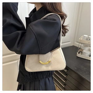 Detail showing high-quality suede texture and golden half-moon buckle on a beige bag