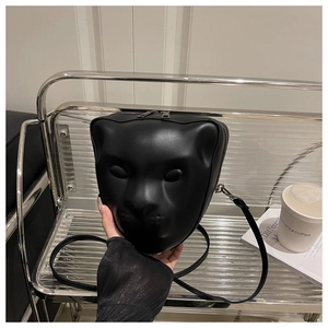 Close-up of a 3D leopard head crossbody bag in matte black leather on a metal shelf