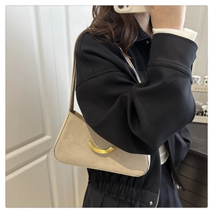 Close-up of a matte suede beige shoulder bag with a golden crescent metal buckle