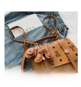 Close-up of brown faux leather polka dot crossbody bag with cute bear charm and strap