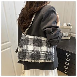 Detail of black and white tweed shoulder bag with fringe edges and gold chain strap