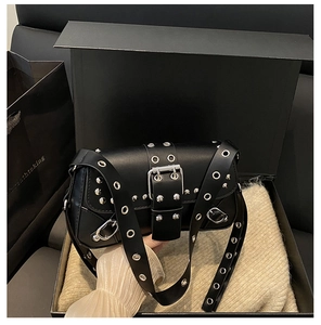 Detailopname van zwarte punk baguette tas met zilveren metalen oogjes en klinknagels