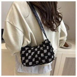 Detail of plaid shoulder bag with frayed edges worn by a model in a modern style