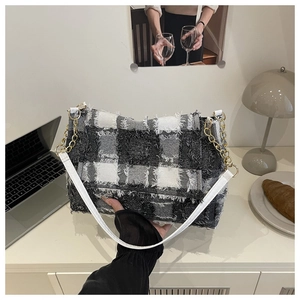 Detail of black and white tweed shoulder bag featuring frayed edges and gold chain strap