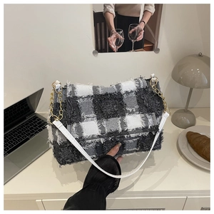 Macro detail of black and white checkered tweed shoulder bag with frayed edges and gold chain