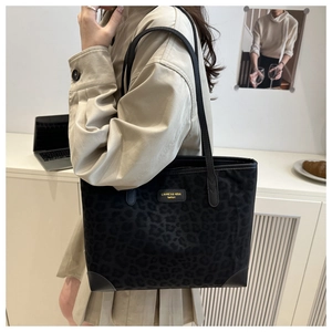 Detail der schwarzen Tote-Bag mit Leopardenmuster und goldenem Logo-Emblem