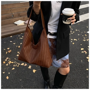 Close-up of brown woven leather texture on a large hobo tote bag in an autumn street setting
