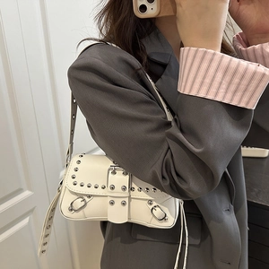 Retro white underarm bag with silver rivets and metal buckles on a stylish shoulder strap