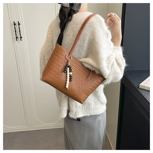 Close-up of brown woven leather tote bag with stylish black and white beaded charm detail