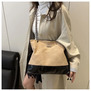 Detail of khaki suede tote bag with diamond quilting and chain strap worn by a model