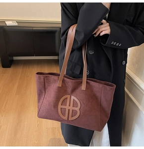 Detail of vintage burgundy suede tote bag with brown leather handles and HB logo