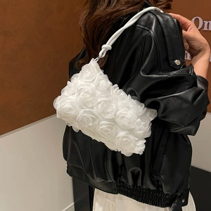 Chic white 3D rose petal shoulder bag with twisted handle shown on model in leather jacket