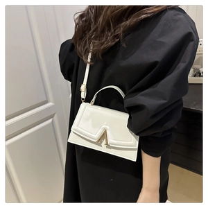 Close-up of a white rectangular bag featuring a glossy finish and a golden V-shaped metal lock