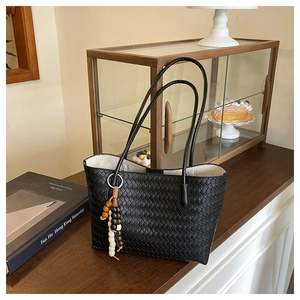 Detail of black woven leather tote bag with multi-colored wooden bead tassel accessory