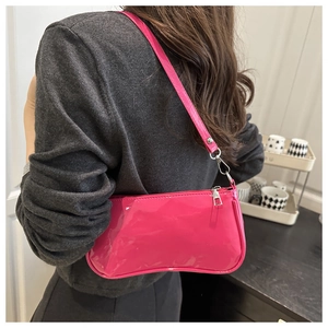 Close-up of rose red glossy patent leather hobo bag with silver zipper and shoulder strap
