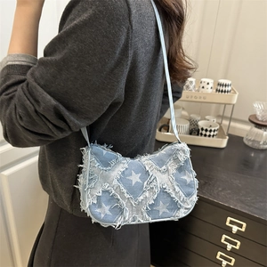 Denim shoulder bag with gradient star patches and fringe detail worn by a model