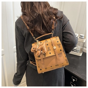 Detailed view of brown monogram backpack with textured pattern and metallic bear charm