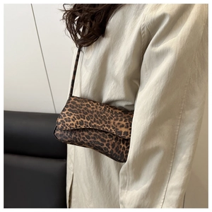 Close-up of leopard print baguette bag on model showing rich fabric texture and slim strap