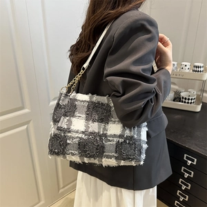 Chic tweed tote bag with fringe detail and gold chain strap shown on a shoulder