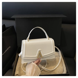 Unboxing detail of a white leather crossbody bag with gold V-clasp in a premium black gift box