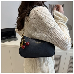 Détail du sac en cuir grainé noir avec chaîne dorée et pendentif cerise rouge