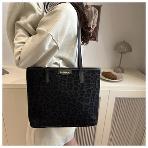 Detail of trendy leopard print tote bag featuring black leather straps and fashion label