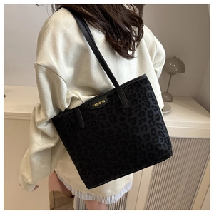 Detail of black leopard print tote bag with thin straps and Fashion brand tag on shoulder