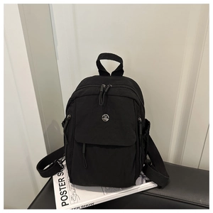 Détail du sac à dos en nylon noir avec logo métallique et finitions zippées