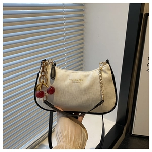 Dettaglio borsa baguette bianca in pelle a grana con charm ciliegia e catena oro