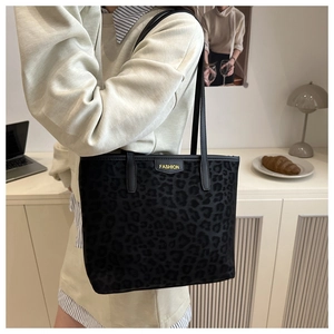 Detail of black leopard print tote bag with yellow fashion label shown on a model