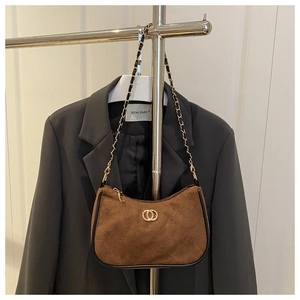 Brown suede underarm bag with diamond stitching and golden chain on a suit background