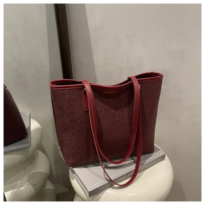 Close-up of wine red leopard print tote bag with Fashion label in minimalist home setting