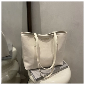 Detail of minimalist cream leather tote bag featuring a Fashion label on a display stool